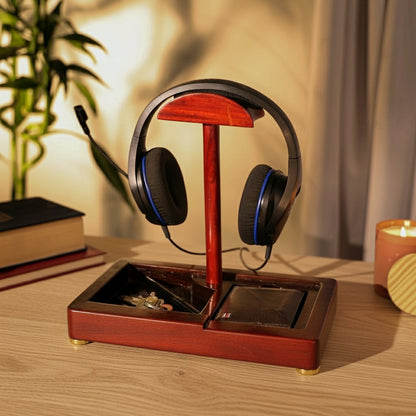 Wooden headphone stand with black headphones on a dark surface with a plant and candle in the background